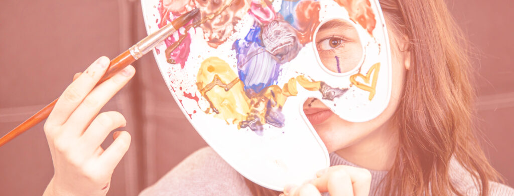Portrait d'une jeune femme tenant une palette pleine de couleurs dans sa main.